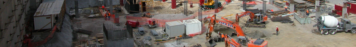 A deep construction pit filled with various heavy machinary.